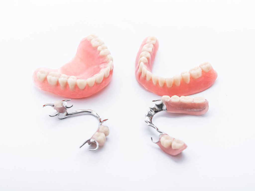 picture of full mouth dentures laying next to partial dentures