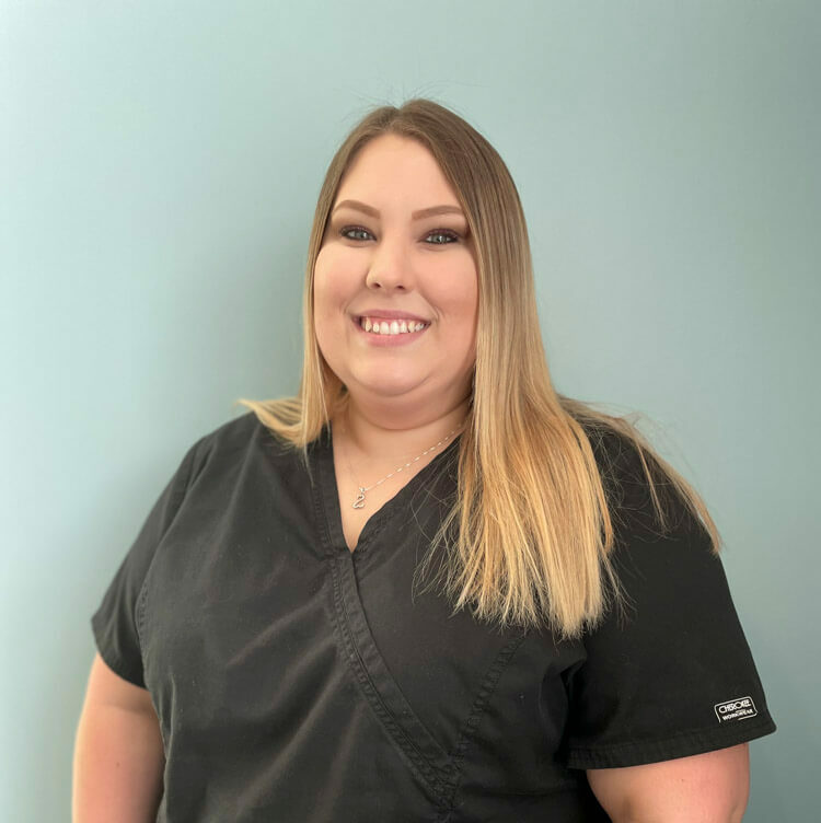 team member kira of horizon dental smiling in front of blue background