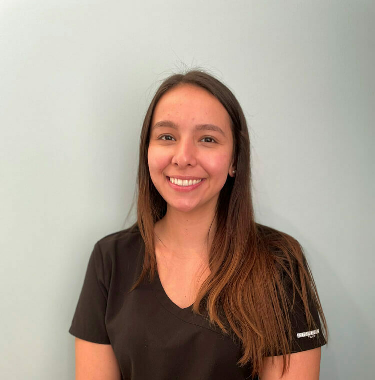 team member trixi of horizon dental smiling in front of grey background